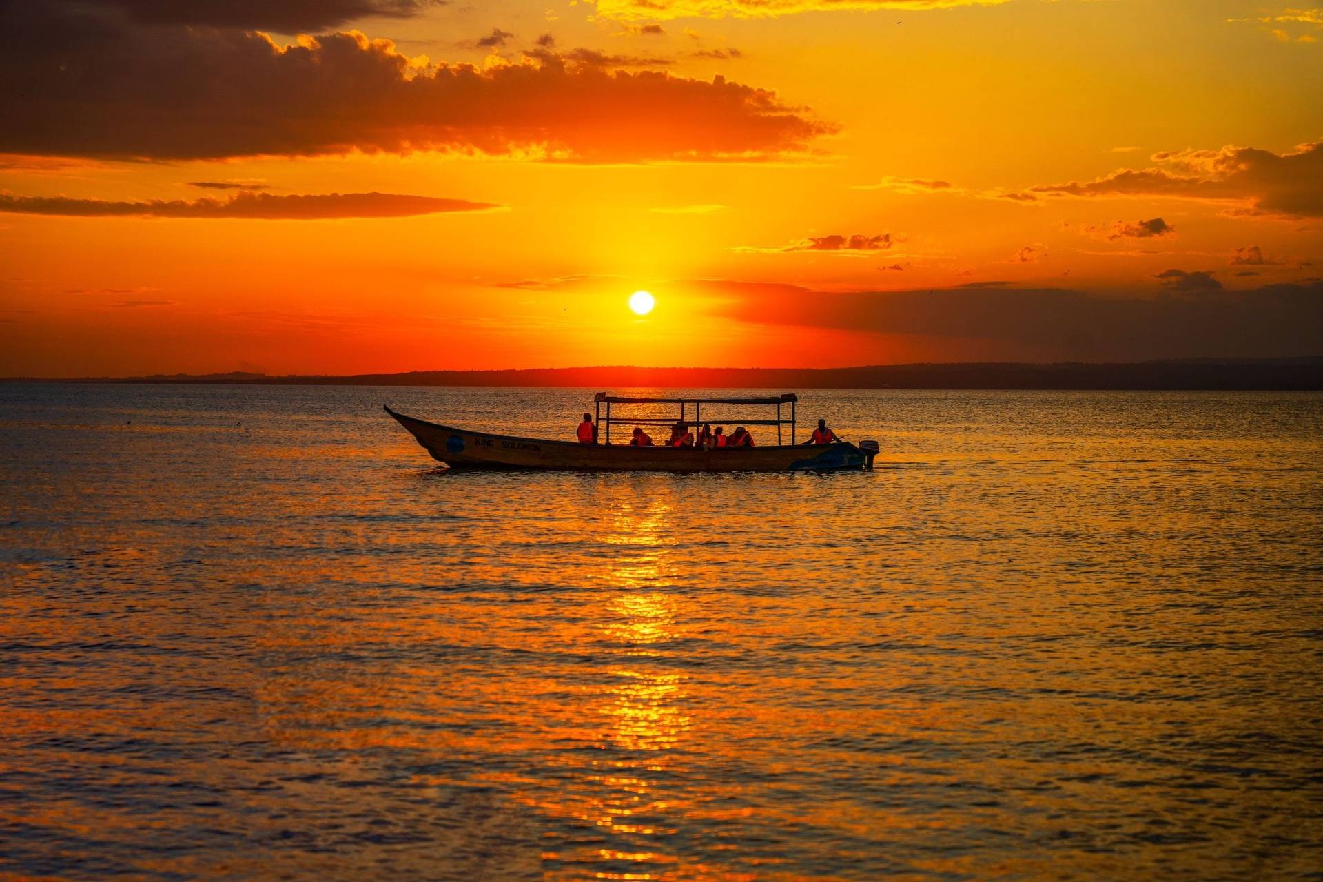 A small boat on open water at sunset, shot from the air
