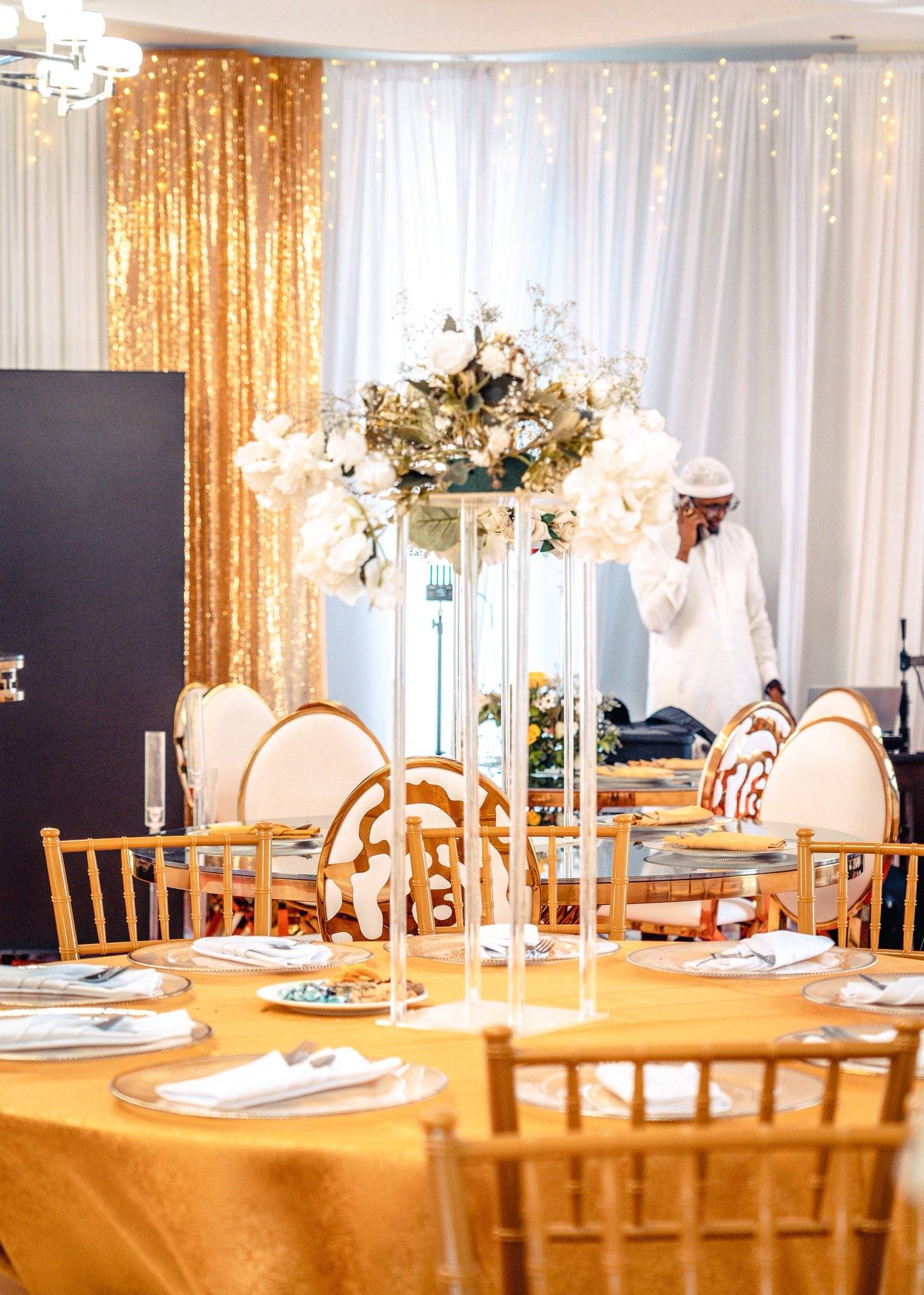 A banqueting room dressed for an event, chairs and florals set